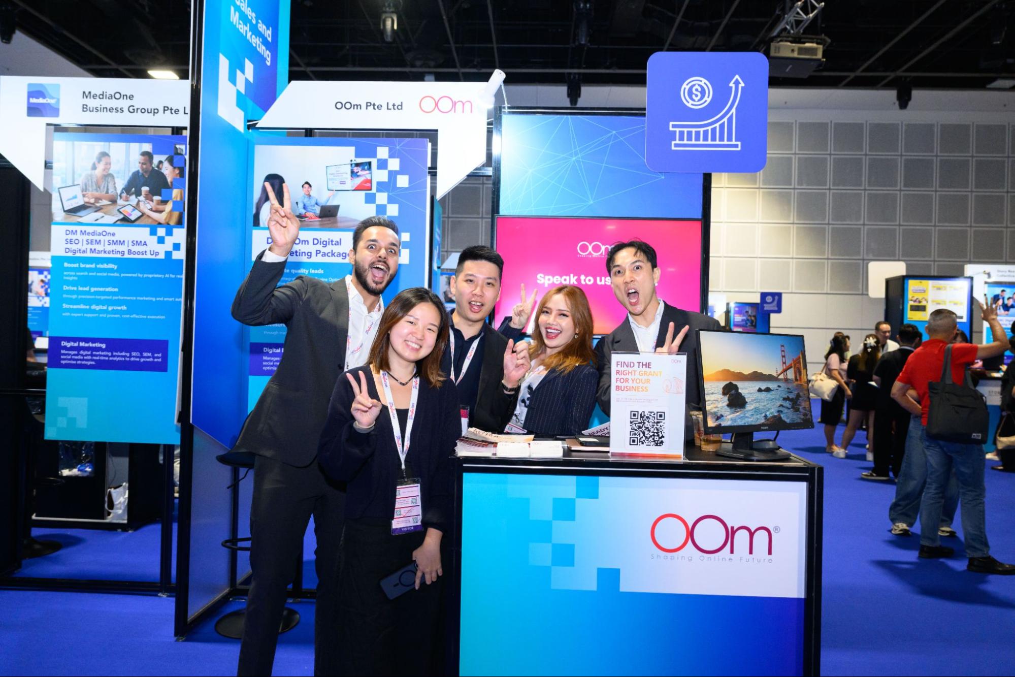 OOm team posing at their exhibition booth